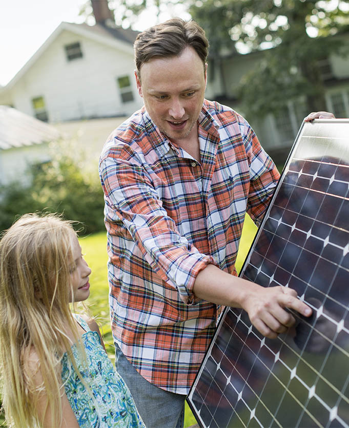 Summer gathering,A man and a young girl looking at a solar panel in a garden.